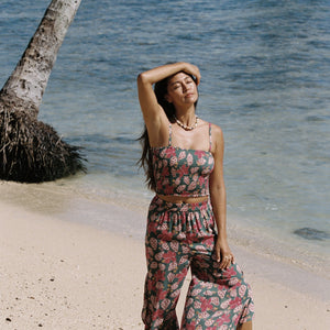 woman with brown hair wearing a teal elastic waist pant with open/slit legs in a shell and pua print