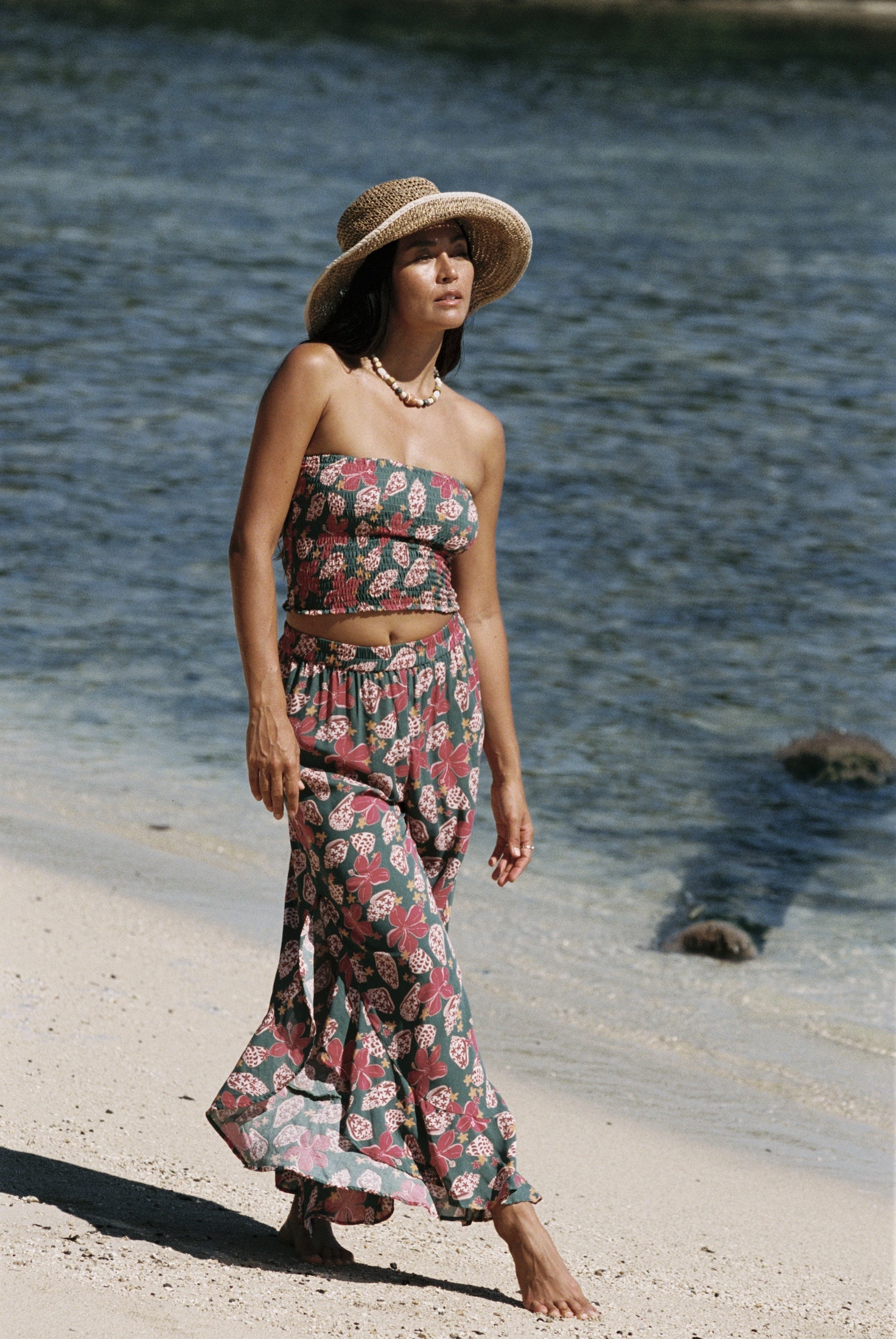 woman with brown hair wearing a teal bandeau top with removable straps with shell and pua print