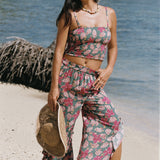 woman with brown hair wearing a teal elastic waist pant with open/slit legs in a shell and pua print