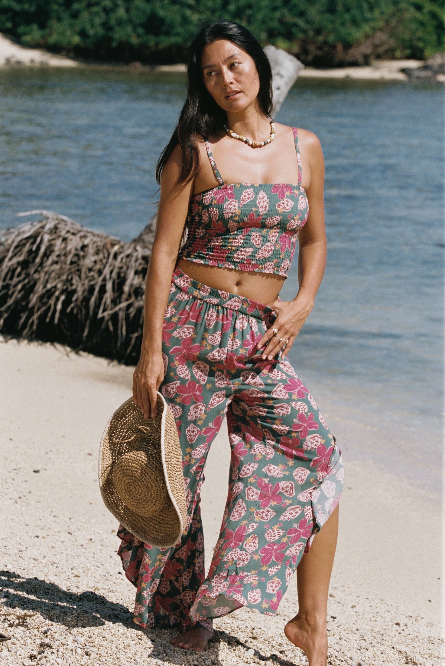 woman with brown hair wearing a teal elastic waist pant with open/slit legs in a shell and pua print
