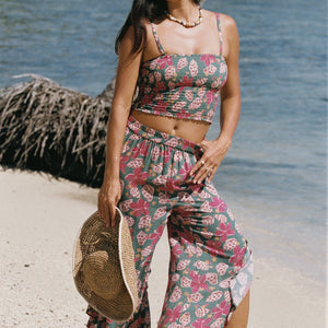 woman with brown hair wearing a teal elastic waist pant with open/slit legs in a shell and pua print