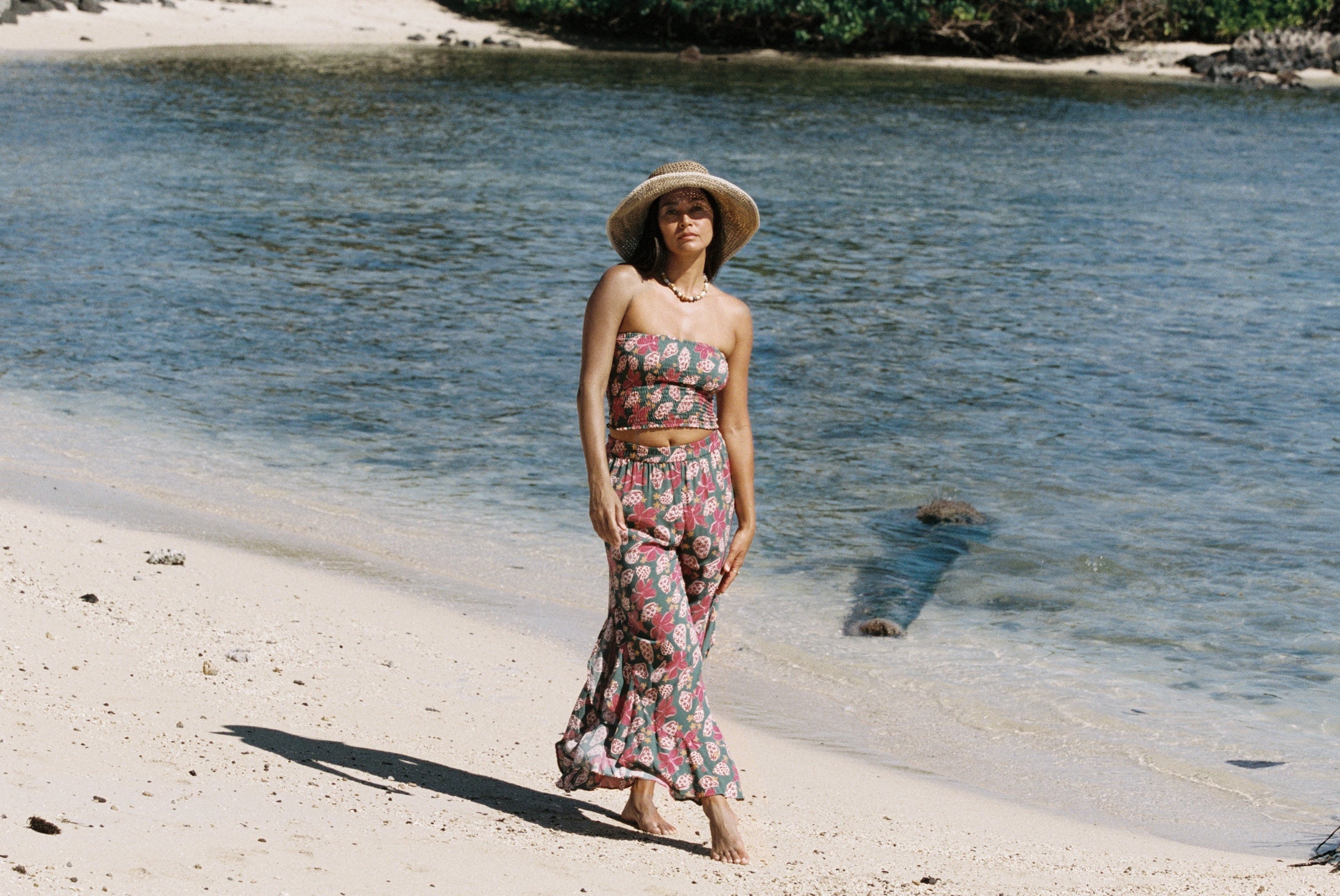 woman with brown hair wearing a teal elastic waist pant with open/slit legs in a shell and pua print