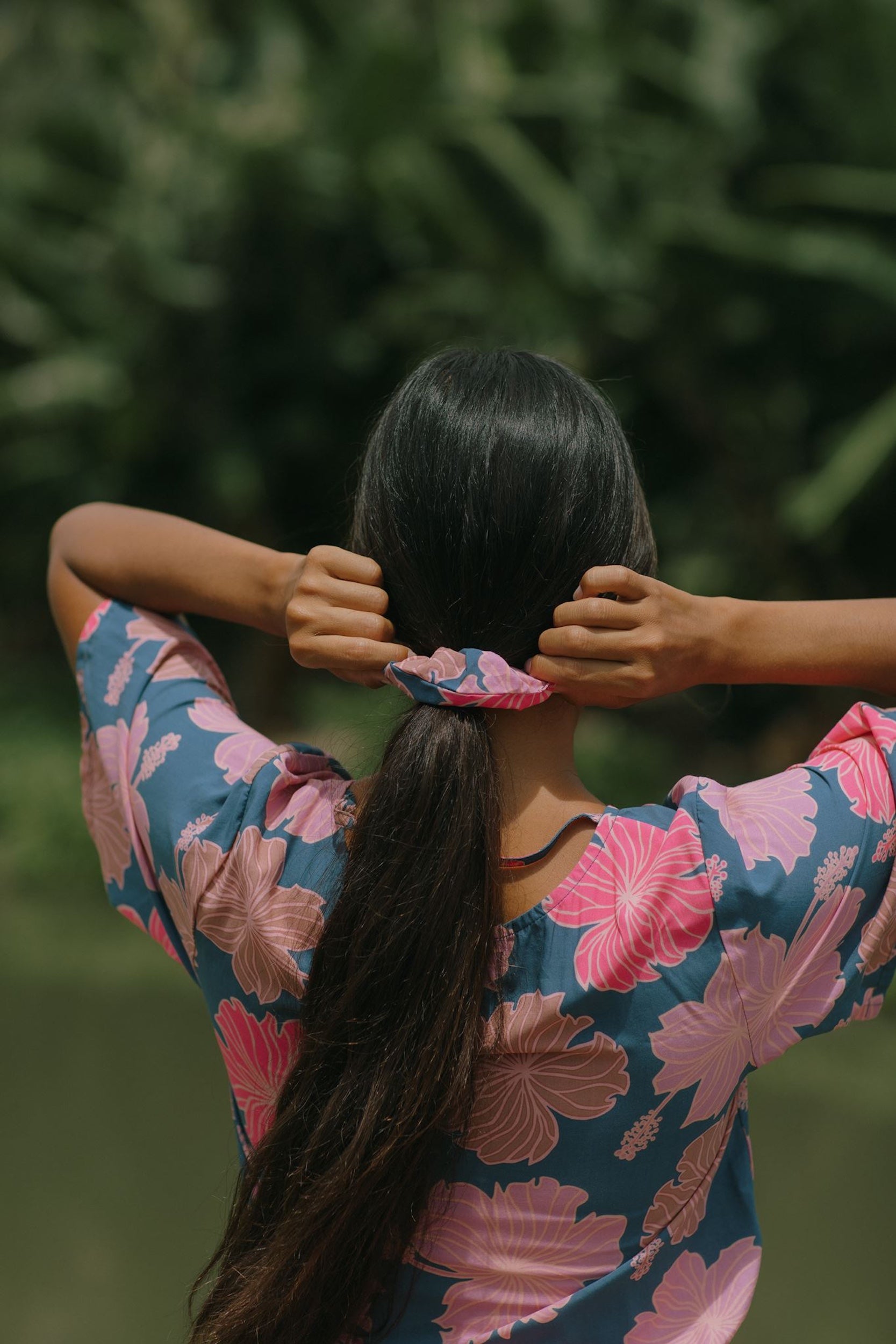 woman with black hair wearing blue and pink scrunchie with hibiscus print