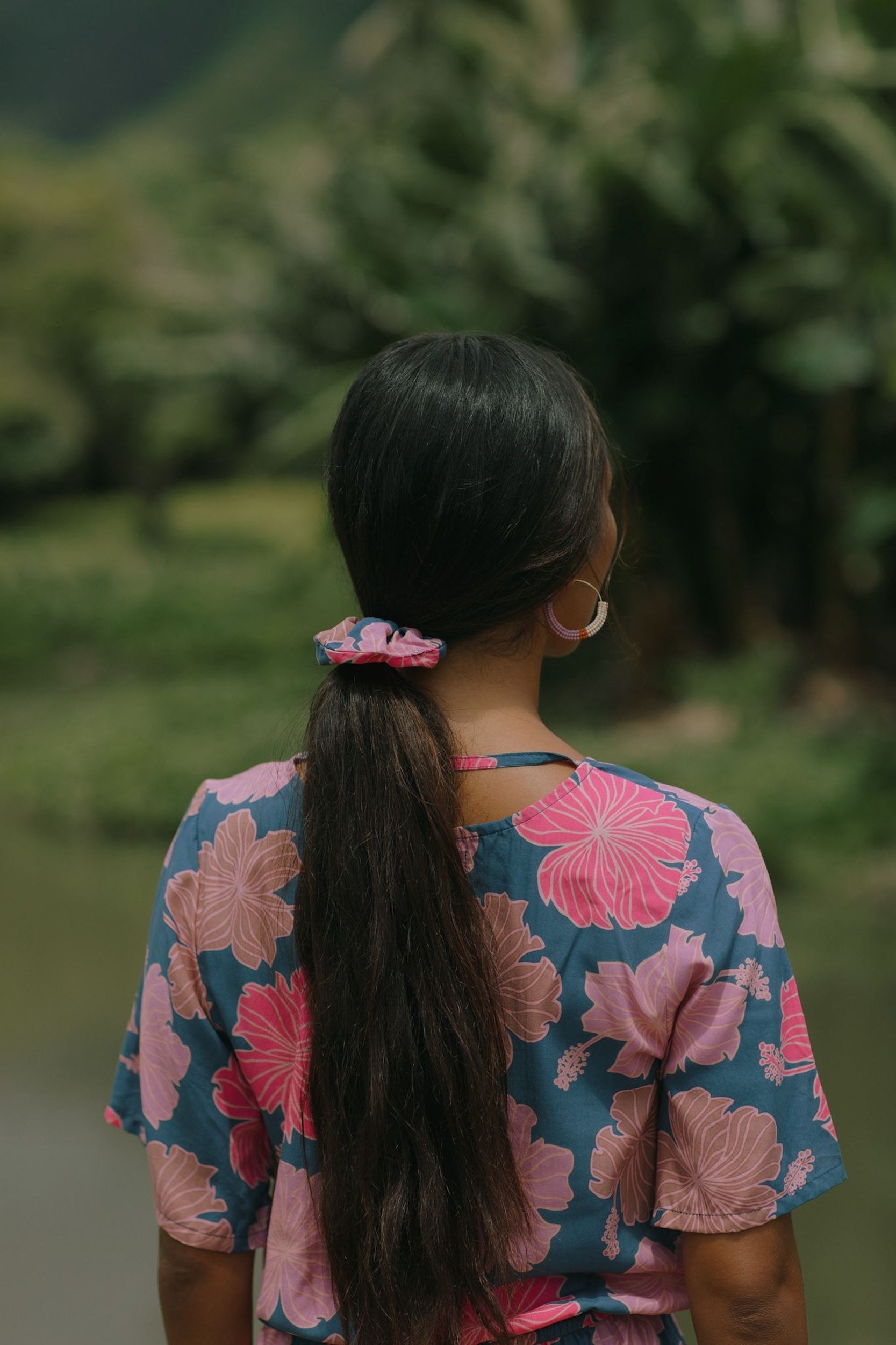 woman with black hair wearing blue and pink scrunchie with hibiscus print