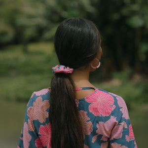 woman with black hair wearing blue and pink scrunchie with hibiscus print