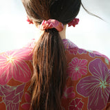 woman wearing terracotta colored scrunchie with large purple and yellow flower print