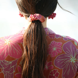 woman wearing terracotta colored scrunchie with large purple and yellow flower print