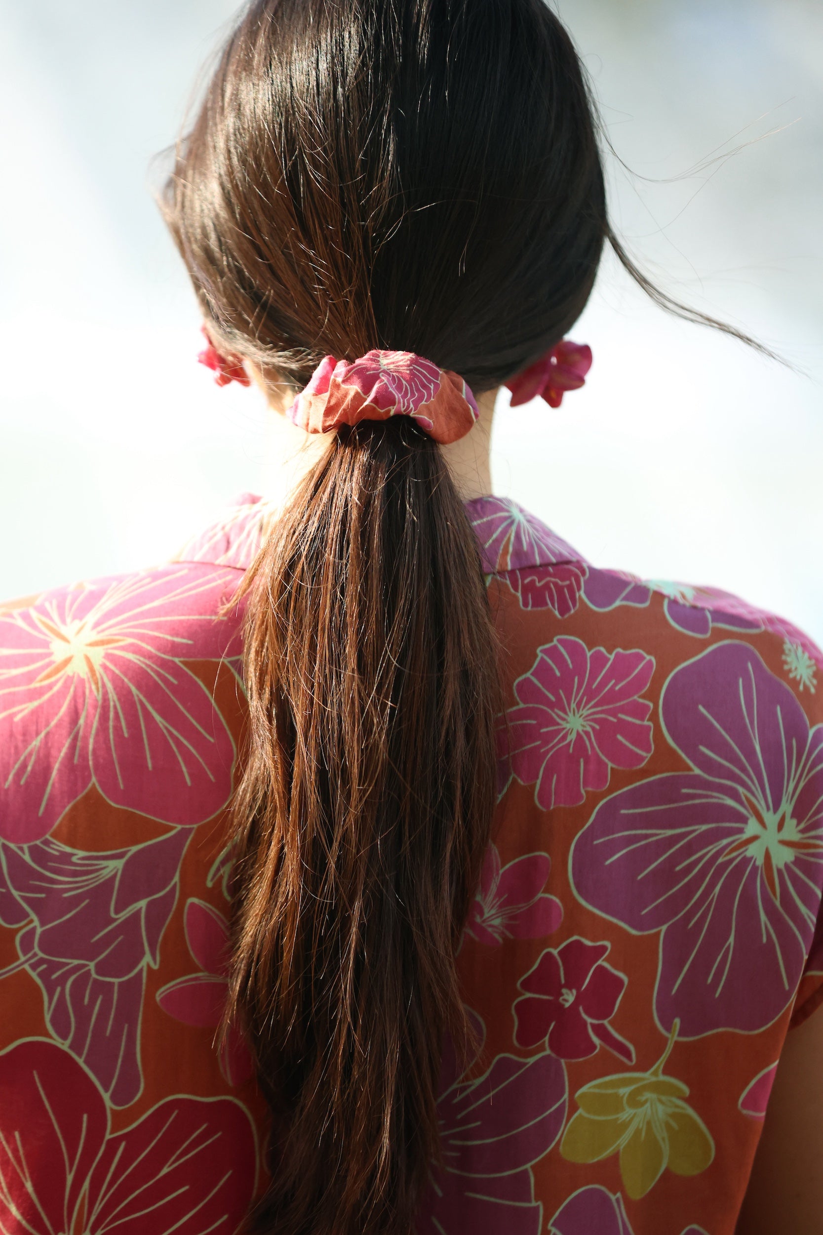 woman wearing terracotta colored scrunchie with large purple and yellow flower print