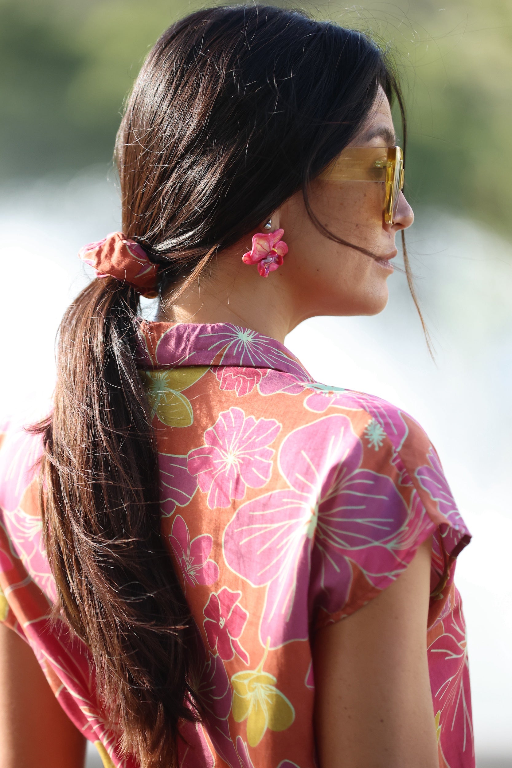 woman wearing terracotta colored scrunchie with large purple and yellow flower print
