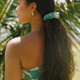 woman with brown hair wearing teal scrunchie with white ginger print
