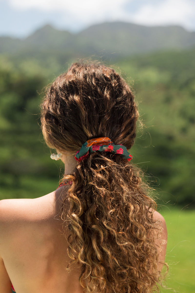 woman with brown hair wearing a colorful scrunchie with tropical lei print