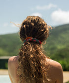 woman with brown hair wearing a colorful scrunchie with tropical lei print