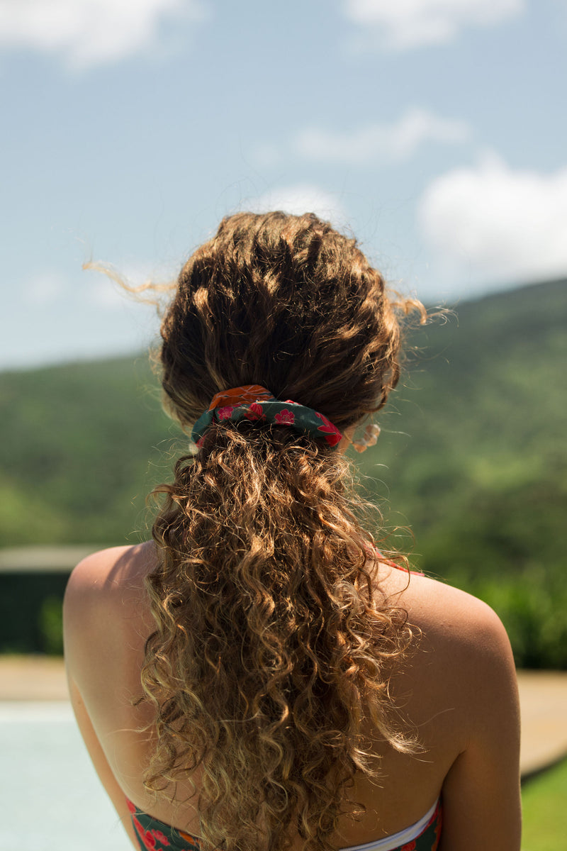 woman with brown hair wearing a colorful scrunchie with tropical lei print