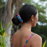 Woman wearing blue scrunchie with pink floral print.