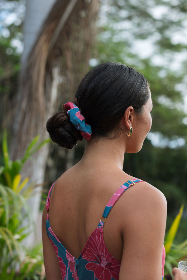 Woman wearing blue scrunchie with pink floral print.