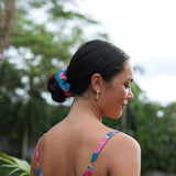 Woman wearing blue scrunchie with pink floral print.