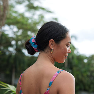 Woman wearing blue scrunchie with pink floral print.