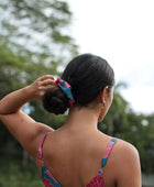 Woman wearing blue scrunchie with pink floral print.