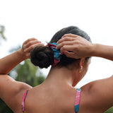 Woman wearing blue scrunchie with pink floral print.