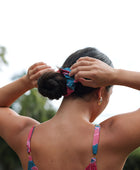 Woman wearing blue scrunchie with pink floral print.