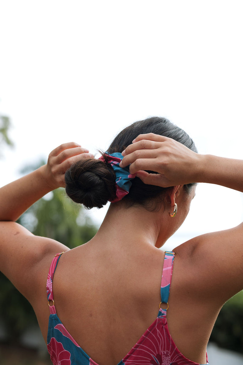 Woman wearing blue scrunchie with pink floral print.