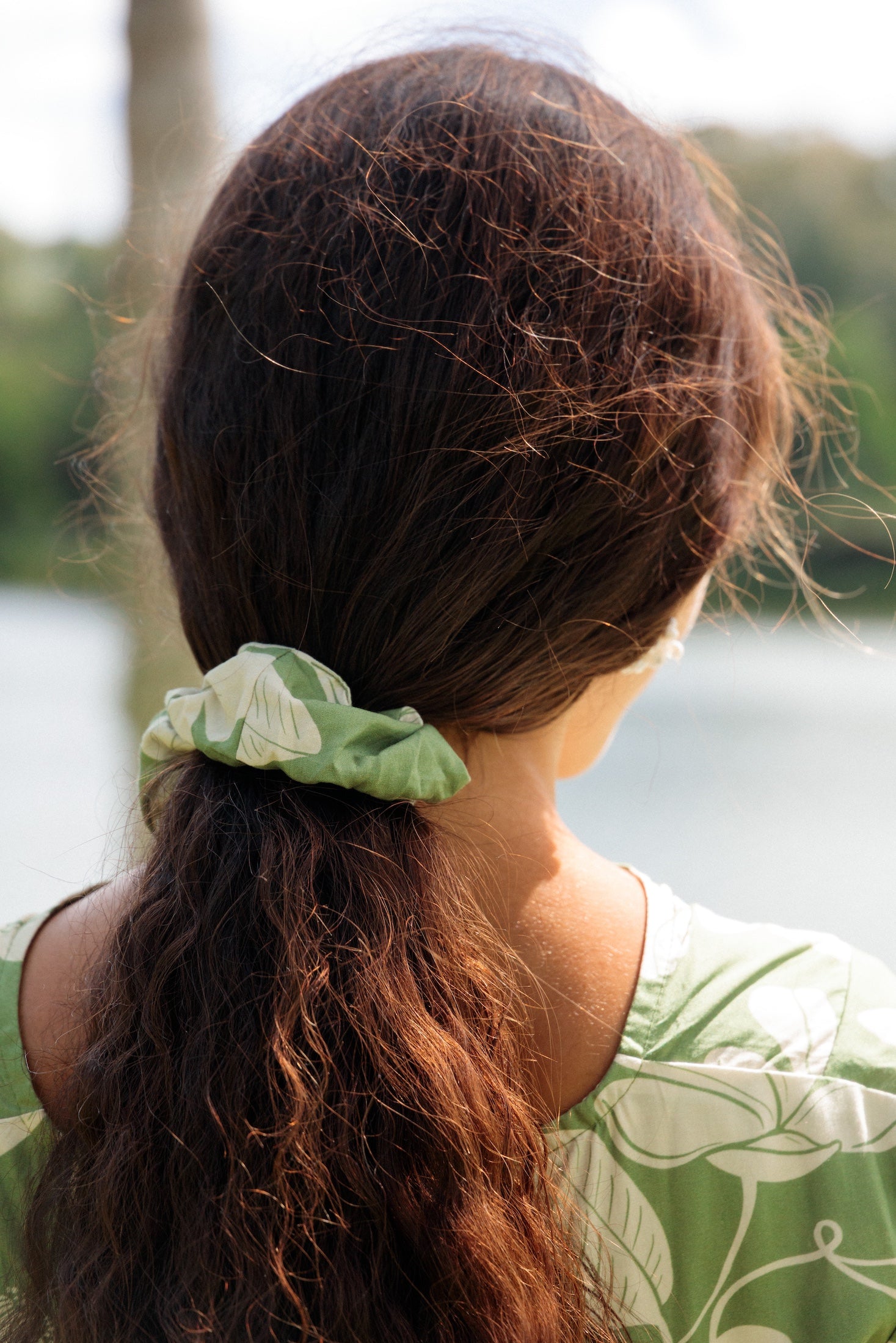 girl with brown hair wearing green scrunchie with native Hawaii plant pattern