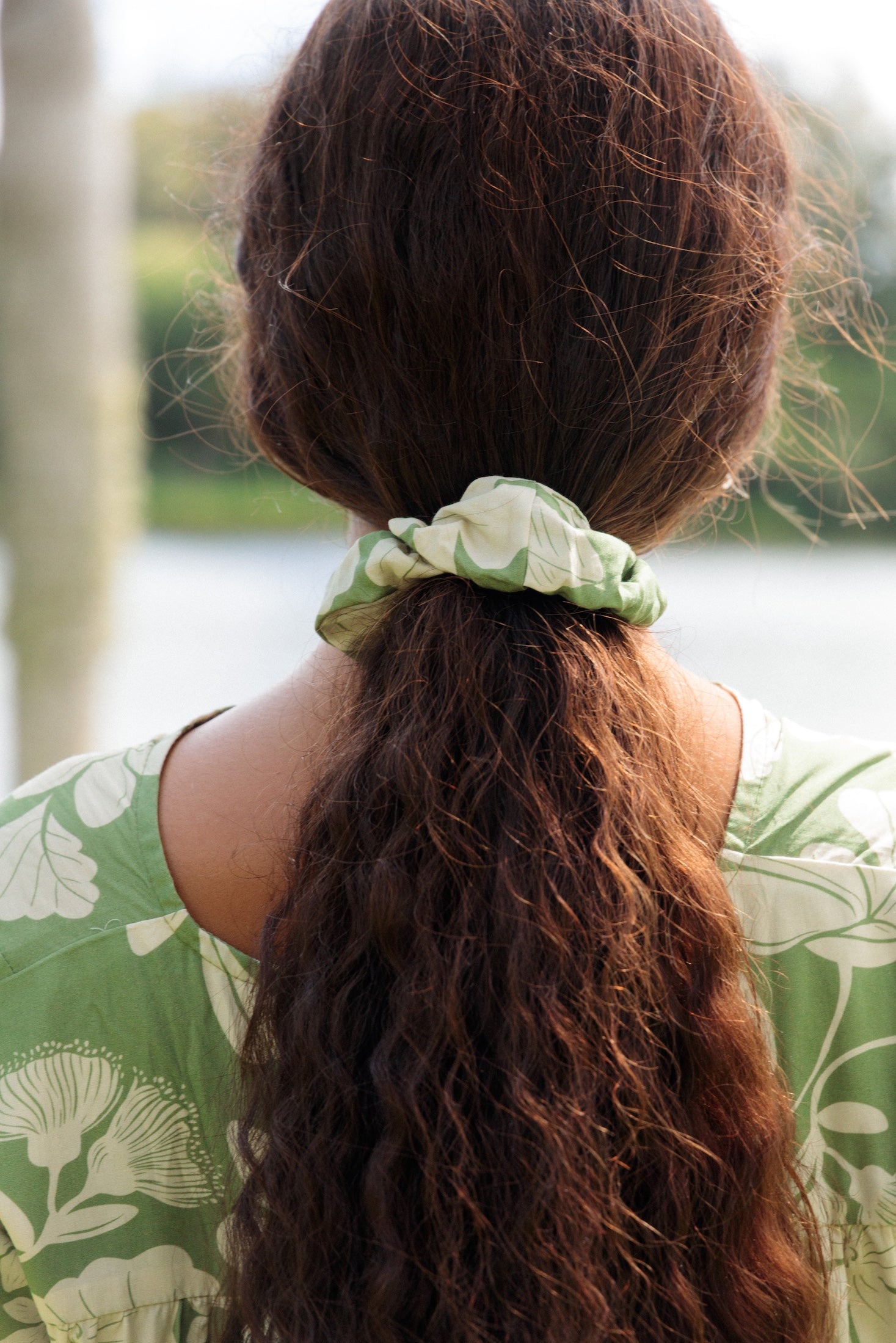girl with brown hair wearing green scrunchie with native Hawaii plant pattern