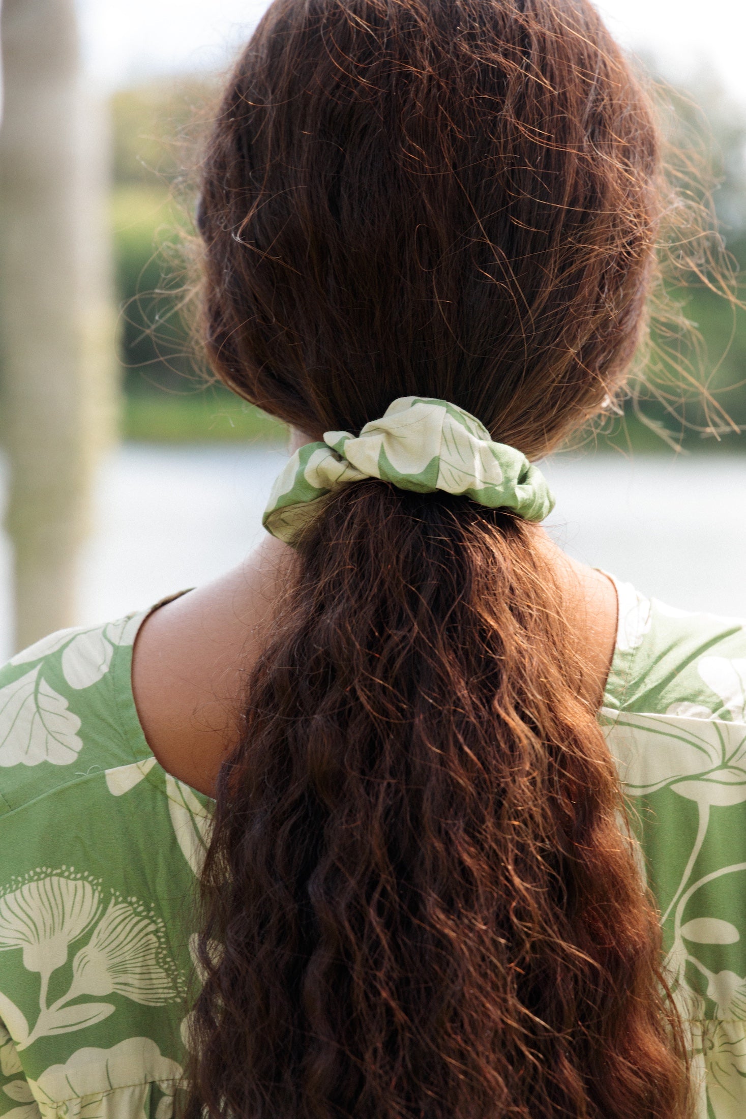 girl with brown hair wearing green scrunchie with native Hawaii plant pattern
