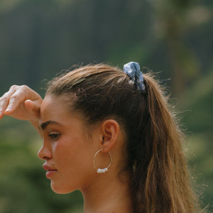 woman with brown hair wearing blue paisley print scrunchie 