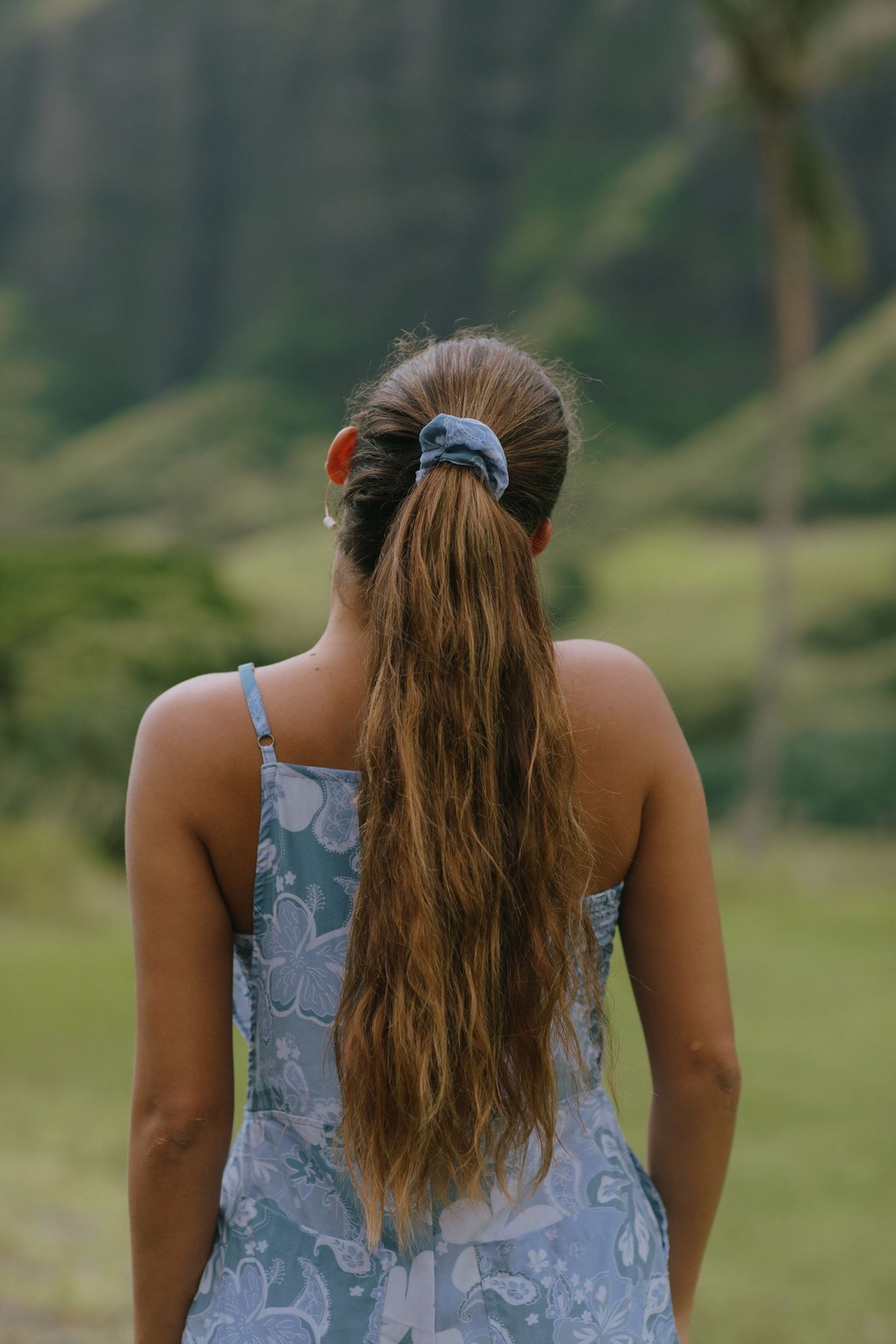 woman with brown hair wearing blue paisley print scrunchie 