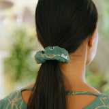 woman wearing lush green scrunchie with puakenikeni print