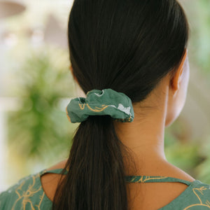 woman wearing lush green scrunchie with puakenikeni print