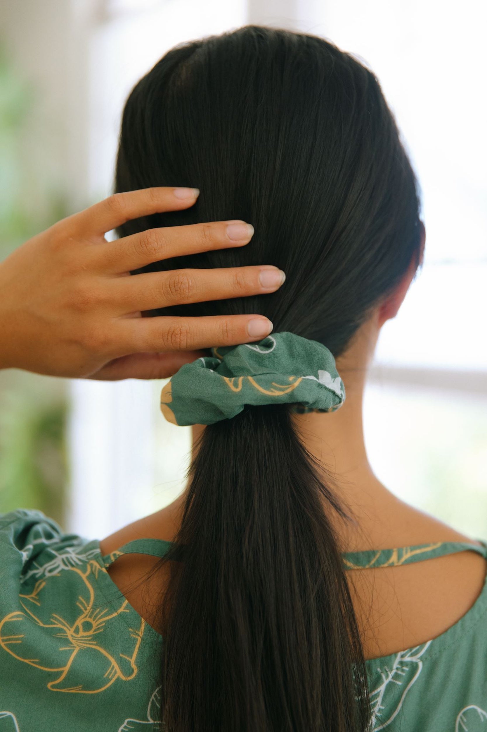 woman wearing lush green scrunchie with puakenikeni print
