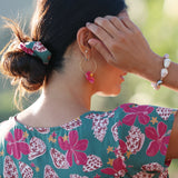 woman wearing a teal scrunchie with shell and pua print