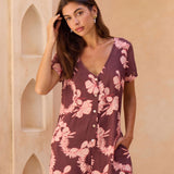 woman with brown hair wearing brown/maroon toned button up romper with pink lei awapuhi print