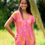 woman wearing a pink button up romper with sleeves with lei print