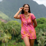 woman wearing a pink button up romper with sleeves with lei print
