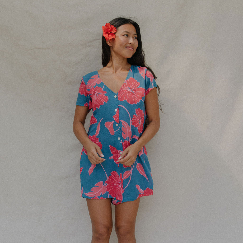 woman with brown hair wearing an aqua button up romper with red mao flower pattern