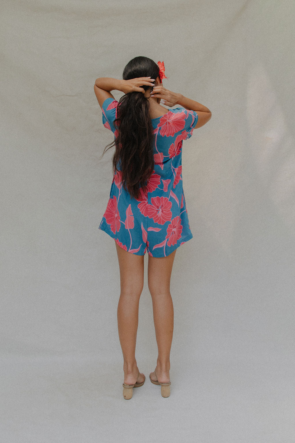 woman with brown hair wearing an aqua button up romper with red mao flower pattern