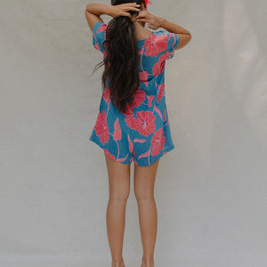 woman with brown hair wearing an aqua button up romper with red mao flower pattern