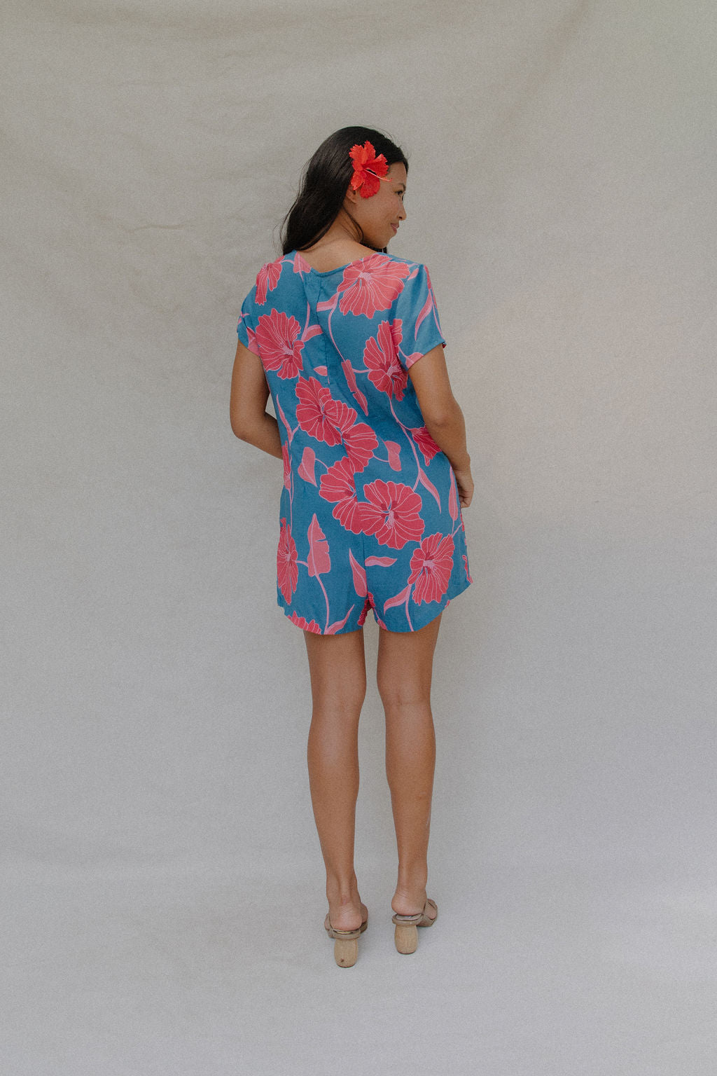 woman with brown hair wearing an aqua button up romper with red mao flower pattern