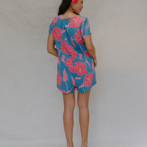woman with brown hair wearing an aqua button up romper with red mao flower pattern
