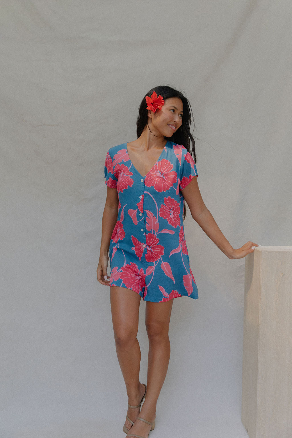 woman with brown hair wearing an aqua button up romper with red mao flower pattern