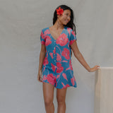 woman with brown hair wearing an aqua button up romper with red mao flower pattern