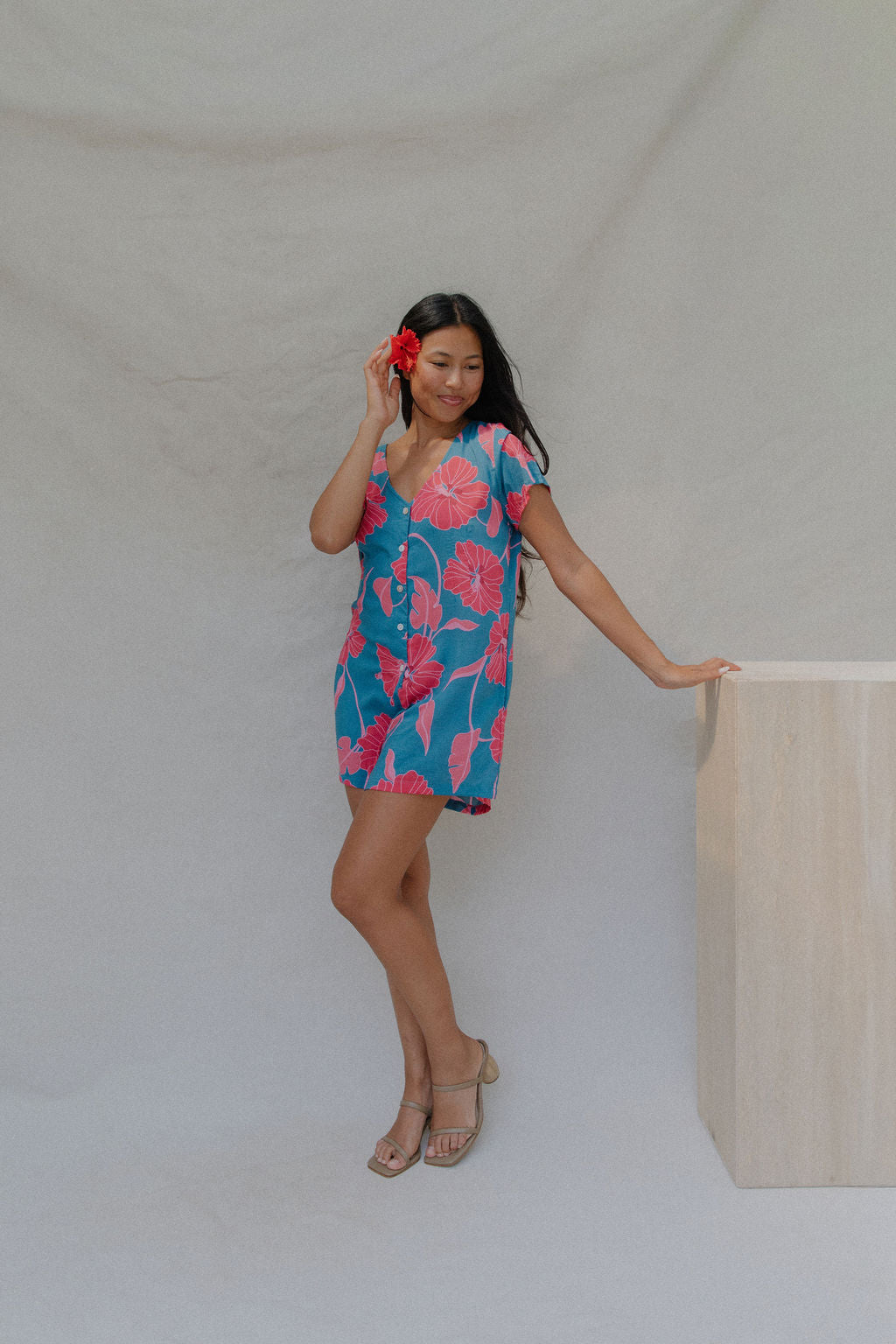 woman with brown hair wearing an aqua button up romper with red mao flower pattern
