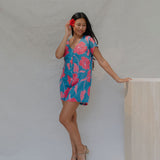 woman with brown hair wearing an aqua button up romper with red mao flower pattern