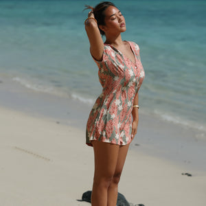 woman with brown hair wearing a jade colored button up romper with tiare ginger print