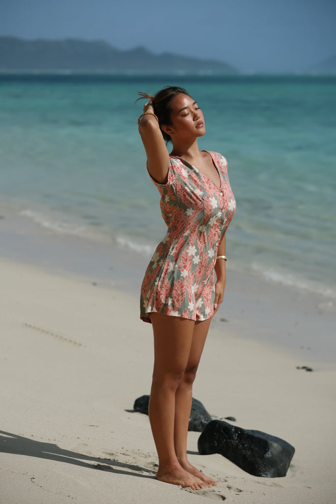woman with brown hair wearing a jade colored button up romper with tiare ginger print