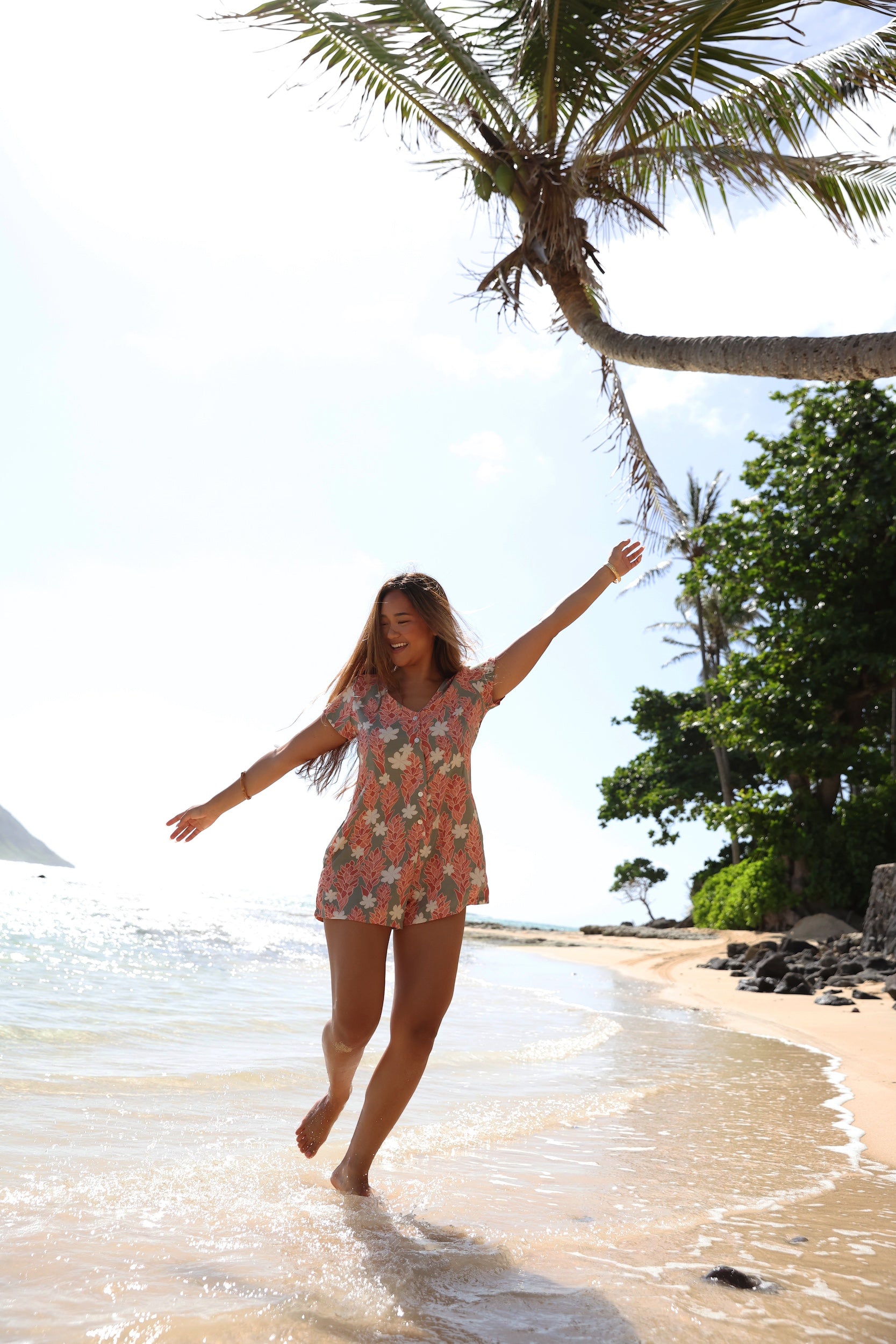 woman with brown hair wearing a jade colored button up romper with tiare ginger print