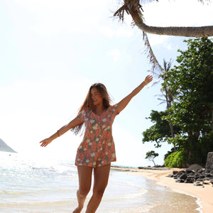woman with brown hair wearing a jade colored button up romper with tiare ginger print